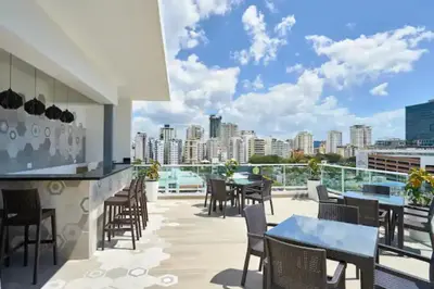a balcony with tables and chairs and a view of the city at Luxury and Cozy Places QDA-II in Santo Domingo