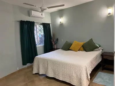 a bedroom with a bed with green curtains and a window at Garden House in Las Galeras