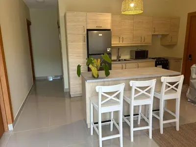 a kitchen with a island with white stools and a counter at Villa Atlantica Punta Cana in Punta Cana
