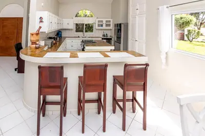 a kitchen with a large island with four chairs around it at Villa Olga in Sosúa