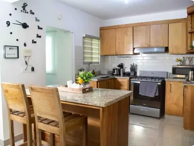 a kitchen with wooden cabinets and a table with chairs at Exclusive Luxury Apartment with Pool in Santiago de los Caballeros
