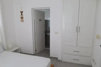 a white bedroom with a bed and a bathroom at Ilaria Bayahibe By Mireya in Bayahibe