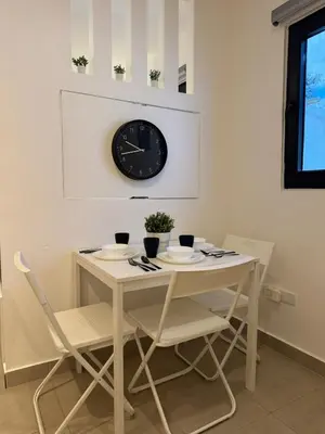 a table and chairs with a clock on the wall at Heyday Studio With Full Kitchenette in Santiago de los Caballeros
