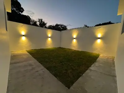 a backyard with lights on a white wall at Heyday Studio With Full Kitchenette in Santiago de los Caballeros