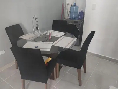 a dining room table with two black chairs and a table at Cómodo Apartamento en Santiago in Santiago de los Caballeros