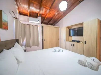 a bedroom with a large white bed and a tv at Colonial 2BR Apartment 2mins walk to beach in Sosúa