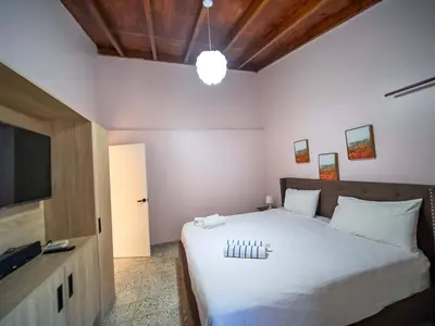 a bedroom with a large white bed with a flat screen tv at Colonial 2BR Apartment 2mins walk to beach in Sosúa