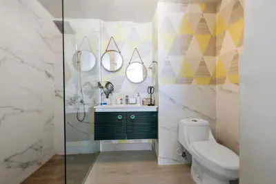 a bathroom with a toilet and a sink and mirrors at 404-C Luxurious Apartment 5 Minutes from the Beach in La Laguna