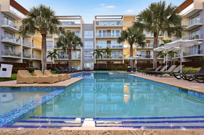a swimming pool with chairs and palm trees in front of a building at 404-C Luxurious Apartment 5 Minutes from the Beach in La Laguna