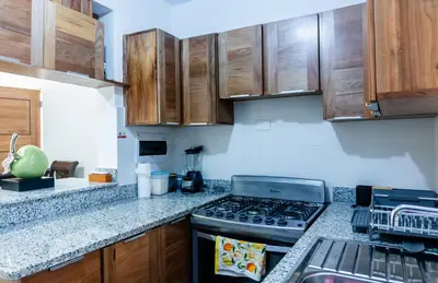 a kitchen with a stove top oven and wooden cabinets at Caribey2 APT 3D1 in Las Terrenas