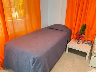 a bed in a room with orange curtains and a table at Mango house bliss in Las Galeras