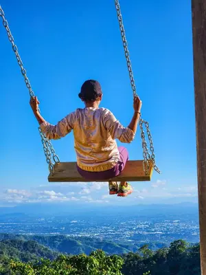 a woman sitting on a swing in the sky at Pure Nature - Eco-lodge in the Mountains! in La Búcara