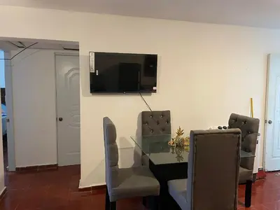 a dining room with a table and a television on a wall at Kasita del sol boca chica in Boca Chica