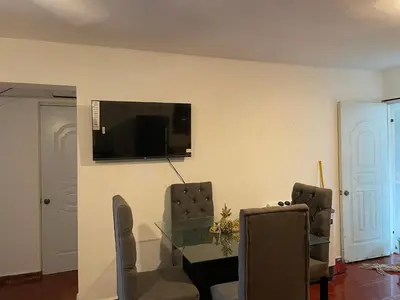 a living room with a table and a tv on a wall at Kasita del sol boca chica in Boca Chica