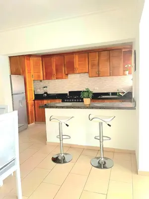 a kitchen with a counter and two stools in it at Modern Apartment, Juan Dolio Beach, BlueSea Tower in Villas del Mar