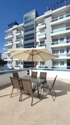a table and chairs with an umbrella in front of a building at Modern Apartment, Juan Dolio Beach, BlueSea Tower in Villas del Mar