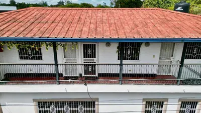 an old white house with an orange roof at Apartamento Mirador de La ciudad in Jarabacoa