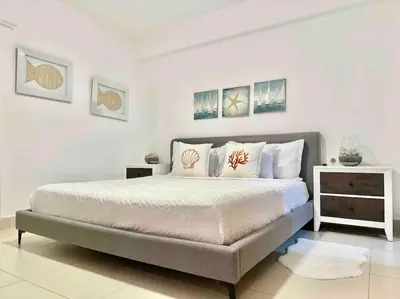 a white bedroom with a large bed with pillows at Cozy Beach Condo Great Views in Guayacanes