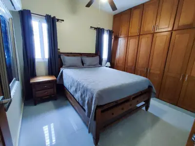 a bedroom with a large bed with wooden cabinets at Sol, playa y arena, Casa cerca de la playa in San Felipe de Puerto Plata