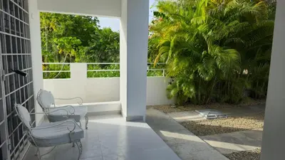 a balcony with two chairs and a palm tree at Acogedora Casa privada in Bayahibe