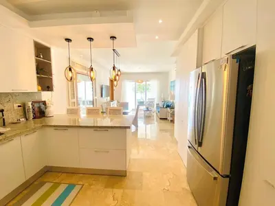 a kitchen with white cabinets and a stainless steel refrigerator at Fortunity1 Escape, Puerto plata Playa Dorada in San Felipe de Puerto Plata