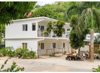 a white house with a palm tree in front of it at El Patio de Lucia Residencia in Las Terrenas