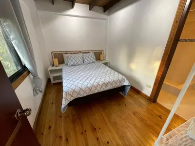 a small bedroom with a bed and a wooden floor at Villa Jarabacoa Monte Bonito in Jarabacoa