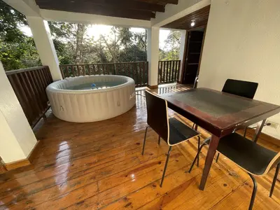 a large tub sitting on a deck with a table and chairs at Villa Jarabacoa Monte Bonito in Jarabacoa
