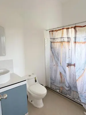 a bathroom with a toilet and a wooden shower curtain at Colina Residence in Las Terrenas