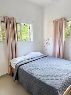 a bed in a bedroom with two windows at Colina Residence in Las Terrenas