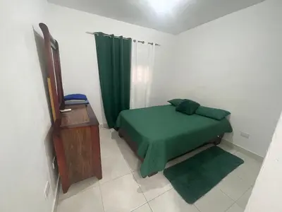 a bedroom with a green bed and a green curtain at Apartamento en Caleta, La Romana in La Romana