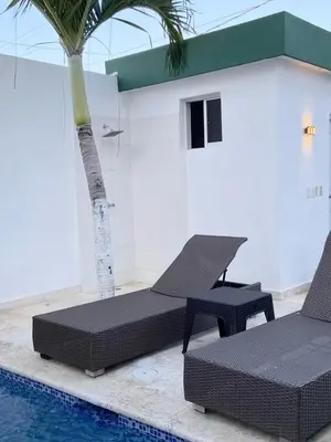 a pool with two lounge chairs and a palm tree at Casa con piscina Romana del Oeste in La Romana