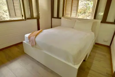 a white bed in a room with two windows at Villa Jimi Las Terrenas in El Naranjito