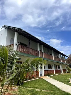 a large white building with a balcony and grass at Apartamento Dani's Guest House con piscina in Las Galeras