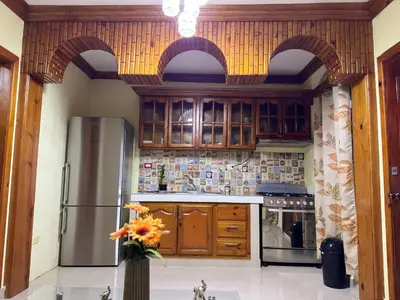 a kitchen with wooden cabinets and a stainless steel refrigerator at Hotel El Bonao in Higuey