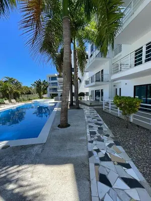 a swimming pool with palm trees in front of a building at Blue apt H1 - two queen bedroom - POOL- in Sosúa
