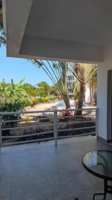 a patio with a glass table and palm trees at Blue apt H1 - two queen bedroom - POOL- in Sosúa
