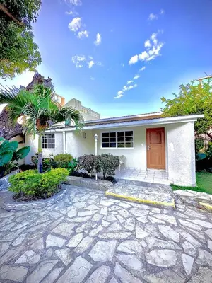 a white house with a red door and a palm tree at Villas Jazmin in San Felipe de Puerto Plata