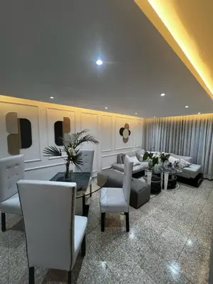 a living room with white furniture and a table and chairs at Comfortable apartment in Santo Domingo