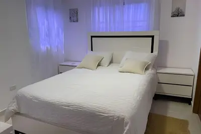 a bedroom with a white bed with white sheets and pillows at Sunshine Palmares de Caleta in La Romana