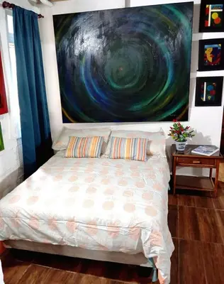 a bedroom with a bed with a painting on the wall at Chalet Thevenin Art Accommodation in Jarabacoa