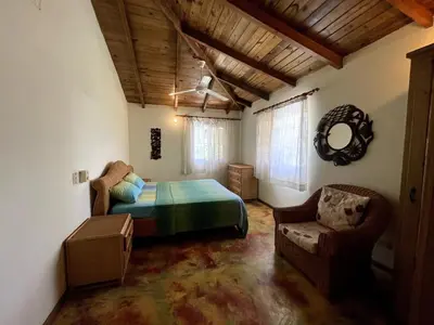 a bedroom with a bed and a chair in a room at Chalet Larimar Charming villa in Las Galeras in Las Galeras