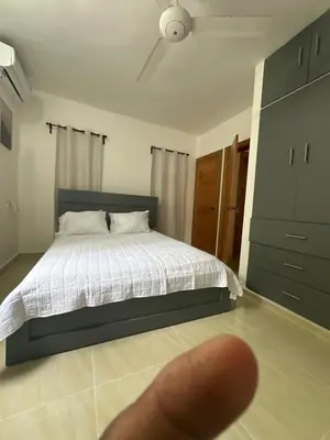 a persons thumb is pointing at a bed in a bedroom at mamajuana House in Las Terrenas