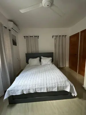 a bedroom with a bed with a white comforter and a ceiling at mamajuana House in Las Terrenas
