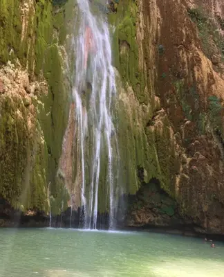 a waterfall on the side of a mountain with a body of water at Lovely Beach Apartment in Tranquil Playa Bonita in Las Terrenas