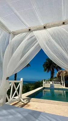 a white canopy over a swimming pool with the ocean at Villa blanca chambre d'hôtes vue sur mer in Las Terrenas