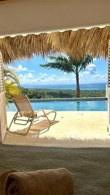a chair and a hammock on a beach with a pool at Villa blanca chambre d'hôtes vue sur mer in Las Terrenas