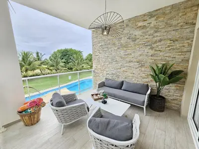 a living room with a couch and chairs and a pool at Luxury Apt with Pool Golf View in Hard Rock Golf in Punta Cana