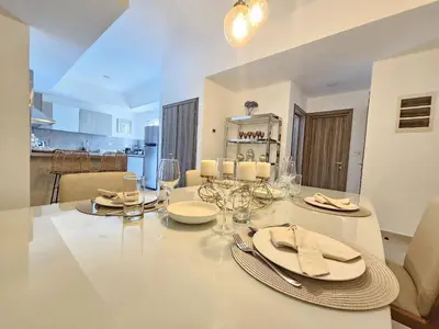 a dining room with a table with plates and wine glasses at Luxury Apt with Pool Golf View in Hard Rock Golf in Punta Cana