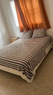 a bed in a room with an orange curtain at apartment for rent in Bayahibe